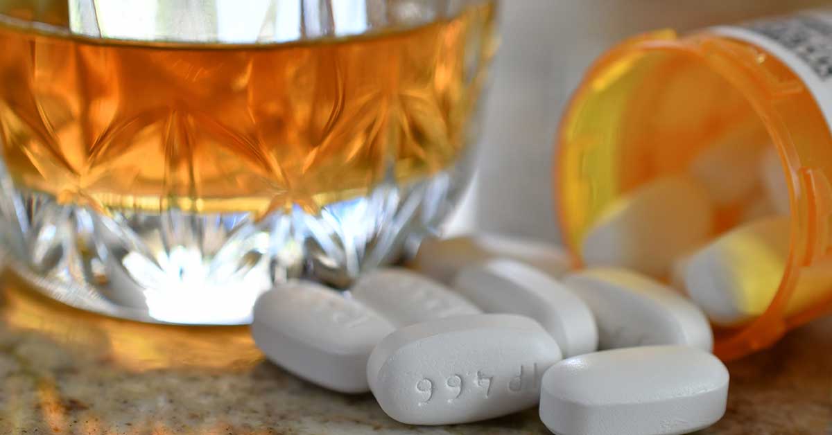 De afbeelding toont een pillendoosje dat citalopram voorstelt en een alcoholische drank ernaast